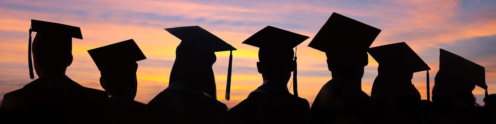 Silhouetted graduates at sunset Silhouetted graduates at sunset