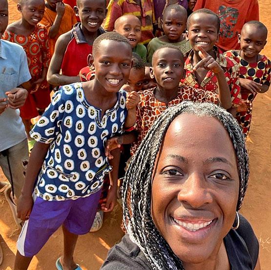Dr. Margie Gill posing with school children in Africa
