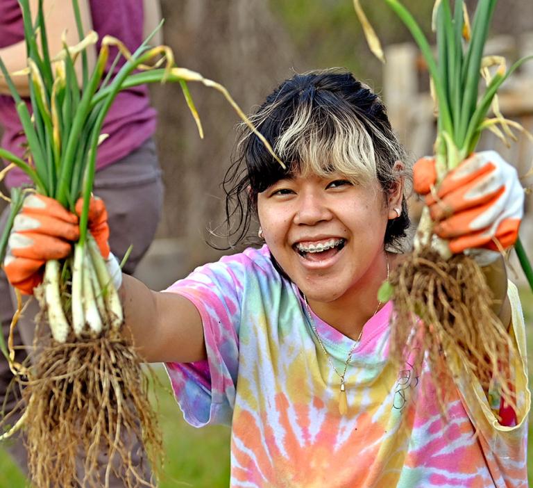 GGC campus microfarm student volunteer holding up green onions