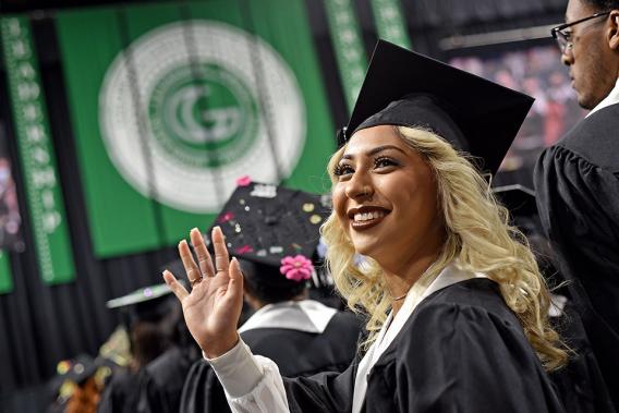 GGC graduate waving to family in audience at commencement ceremony