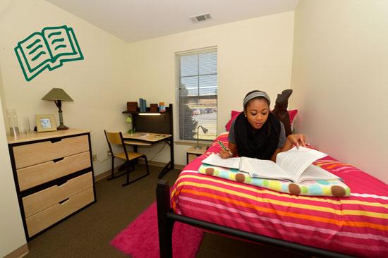 Grizzly resident studying on bed in private room of student housing