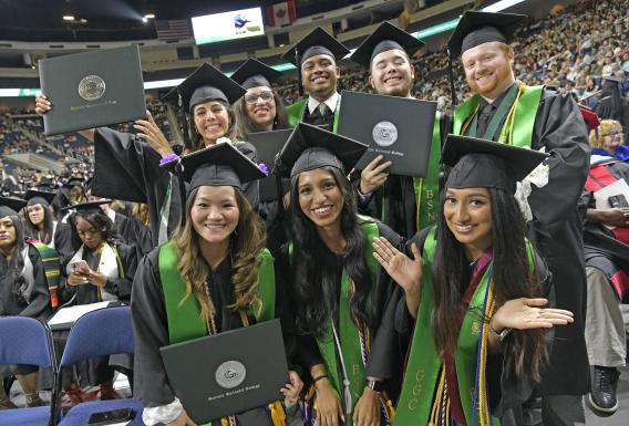 GGC grads at commencement ceremony holding up diplomas