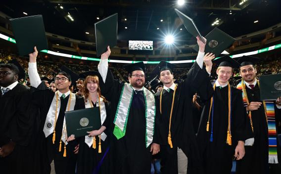 GGC grads at commencement ceremony holding up diplomas
