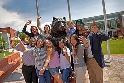 Welcoming students posing with Grizzly statue.