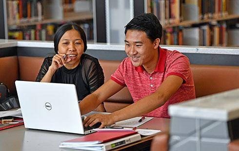 Students collaborating using laptop in the library