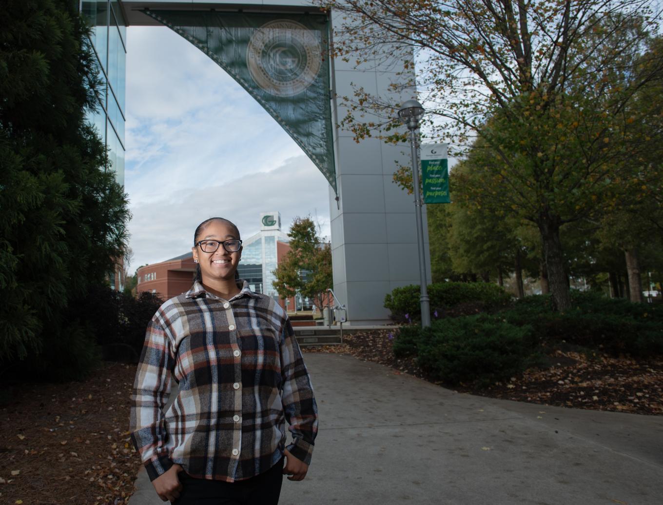 Nia Mallory posing near the Arch of Knowledge and library