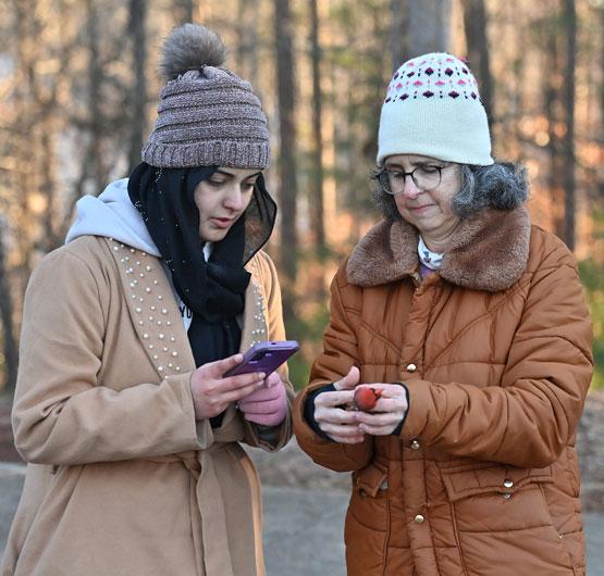 Sara Rabab takes a photo of a cardinal, held by Maria Fernandez, as they work on banding him at Collins Hill Park.