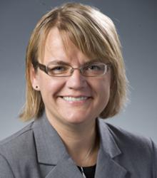 Dr. Dovile Budryte wearing glasses and gray jacket smiling at camera