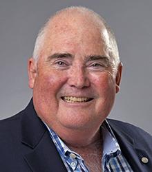 Dr. Michael Gagnon wearing a blue striped shirt and blue jacket smiling at camera