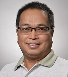 Dr. Melchor C. de Guzman smiling at camera