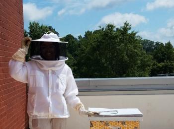 Giana Jeanty, a Chemistry major, installs a hand-painted honey super of her own design, blending science and creativity to support campus beekeeping efforts.