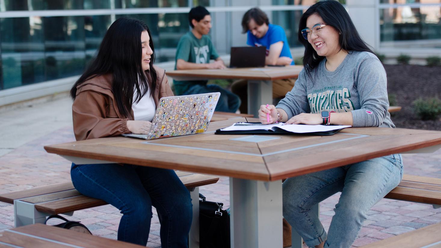 Four students sitting at outdoor tables