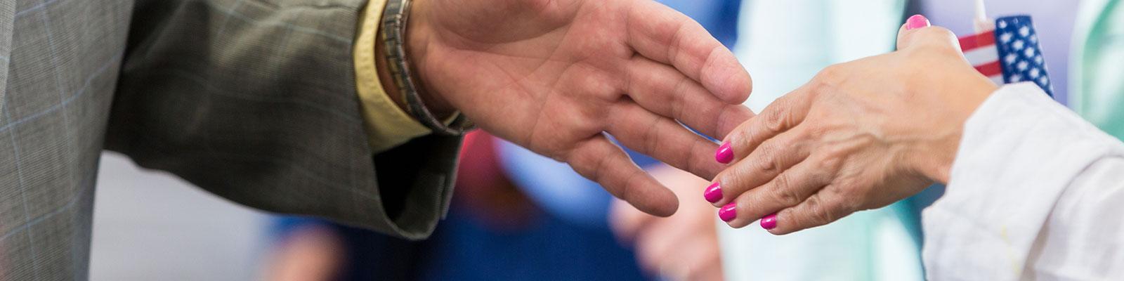 two people shaking hands with U.S. flag in background two people shaking hands with U.S. flag in background